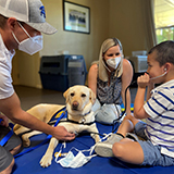 three people with a Canine Companions service dog