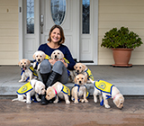 woman seating in front porch with litter of puppies