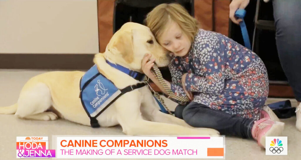 Young girl, Alexis, hugging her service dog Clifford