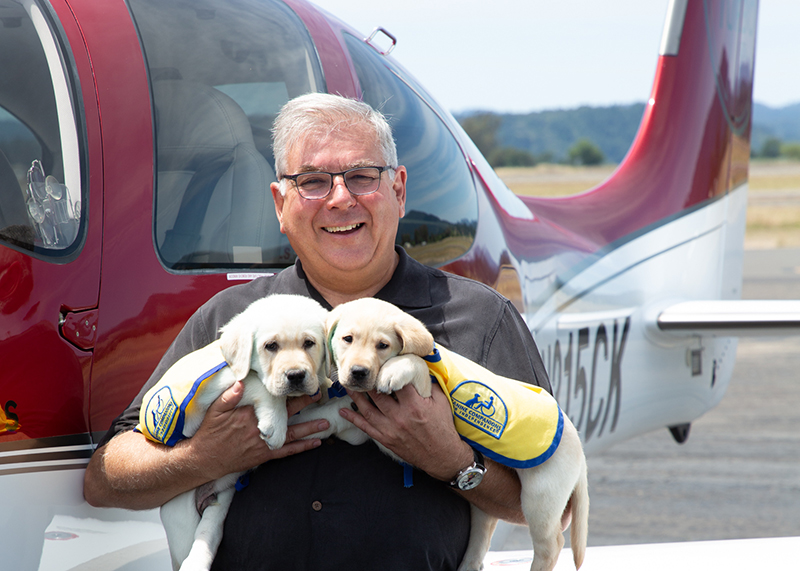 pilot holding 2 puppies
