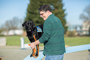 man training a Canine Companions dog in park