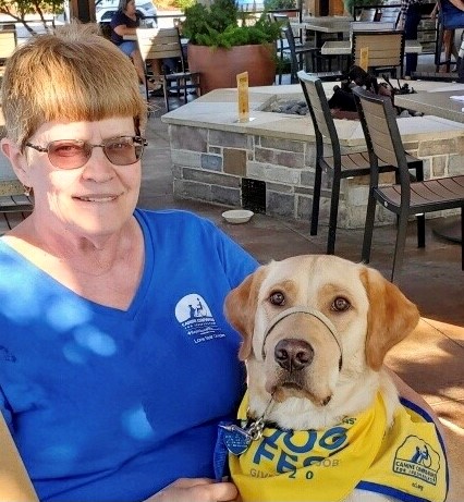 a woman sitting with a yellow puppy