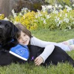 Young girl hugging Canine Companions service dog