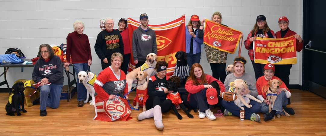 group of people with Chiefs merch and Canine Companions puppies