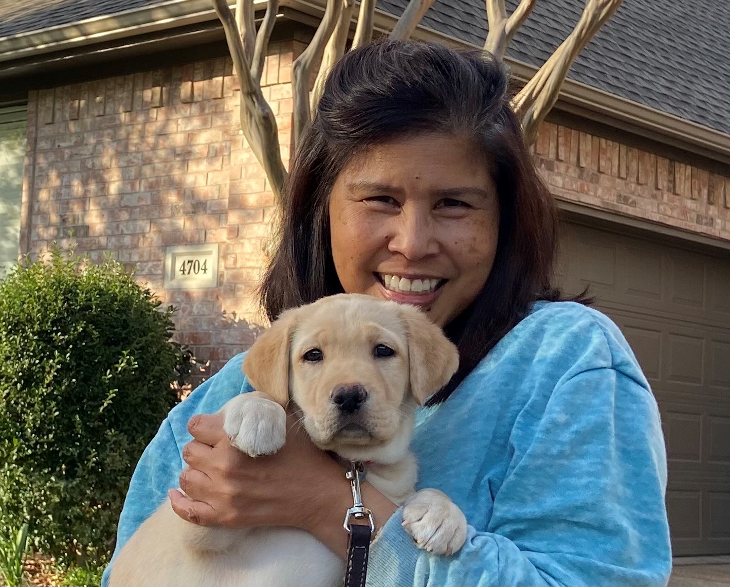 woman holding a yellow puppy