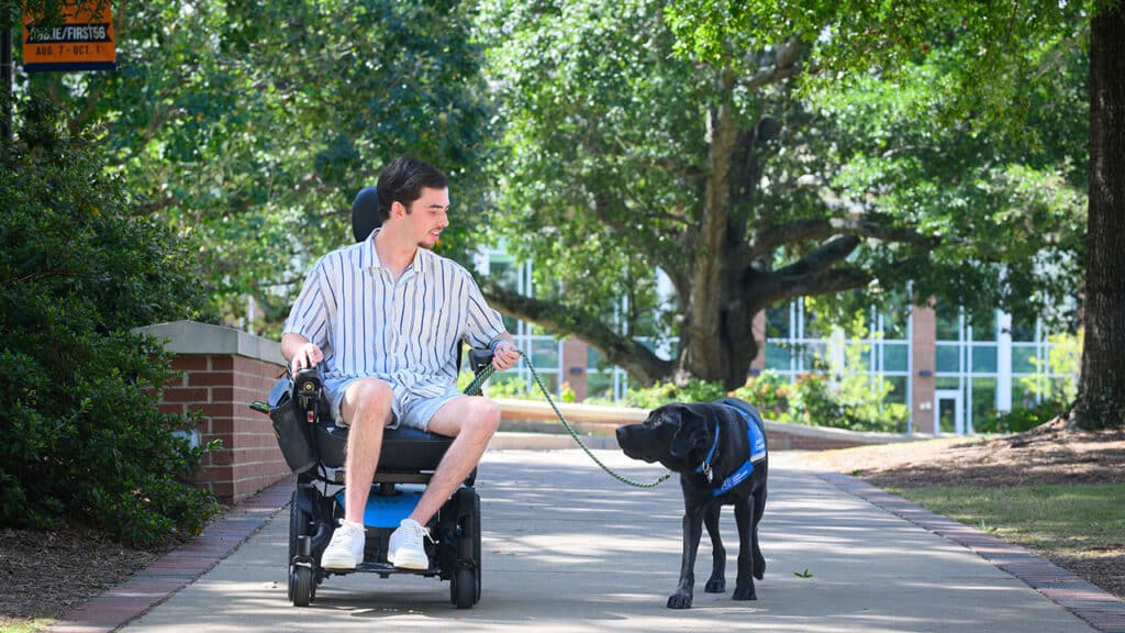 Photo of Noah in a wheelchair and service dog Schooner side by side