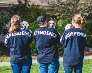 3 people holding puppies and wearing Independence jerseys