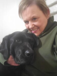 a woman holding a black puppy