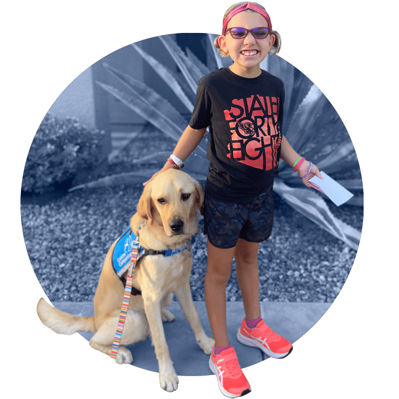 a smiling young girl with a yellow lab in a blue service vest sitting next to her