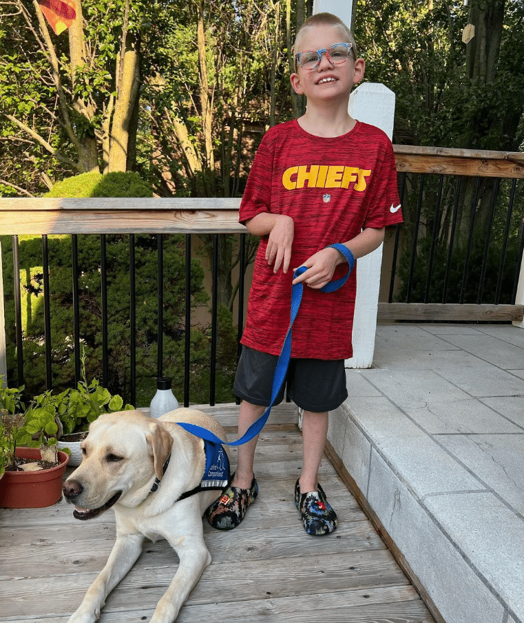 Canine Companions graduate Patrick poses in a Chiefs jersey with service dog Julio.